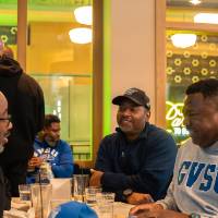 Group of event attendees sitting at booth and chatting